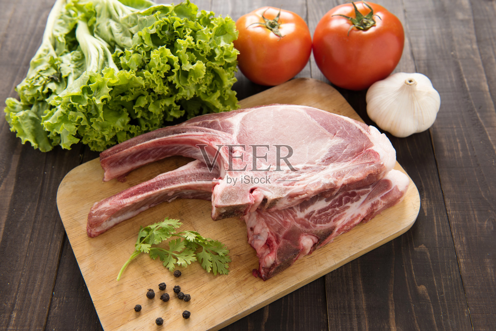 新鲜的生猪排和蔬菜在木制的背景。照片摄影图片