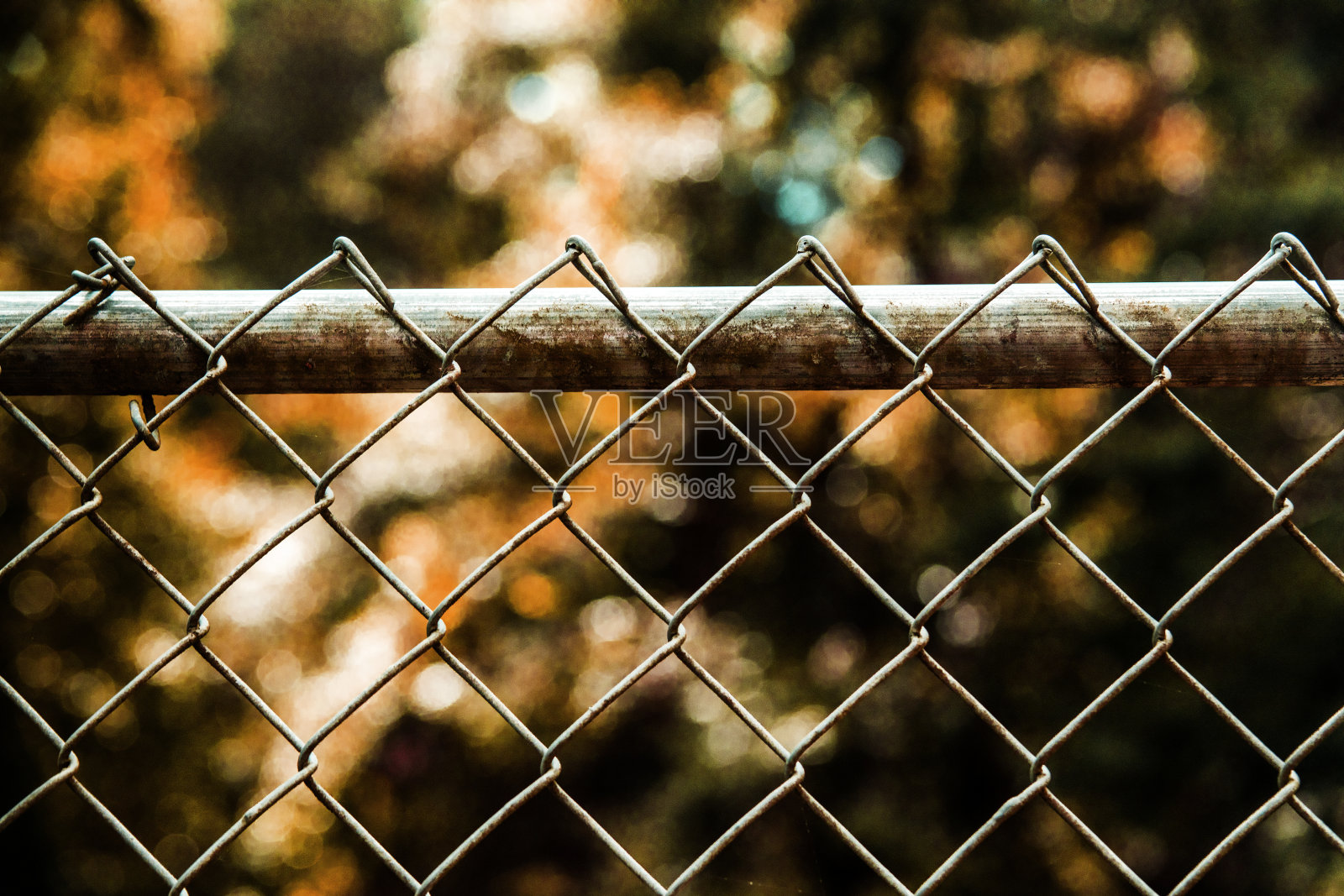 铁丝栅栏和木桩。锈橙色背景和色调。照片摄影图片