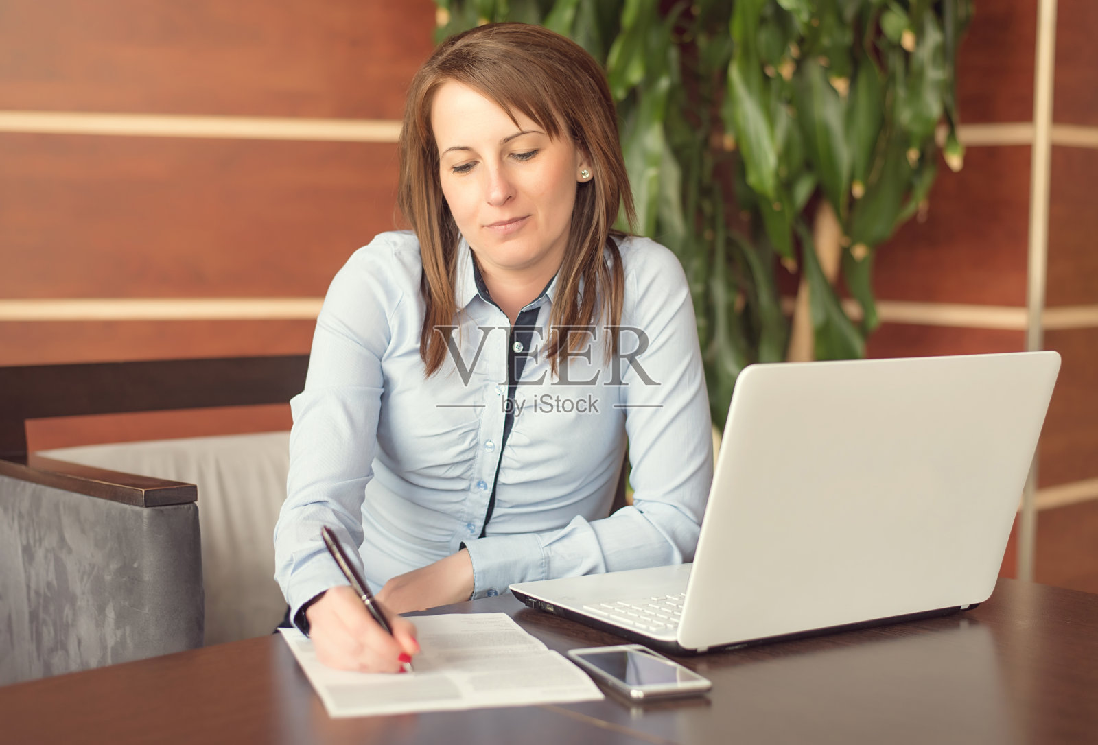 坐在办公室扶手椅上的可爱女人照片摄影图片