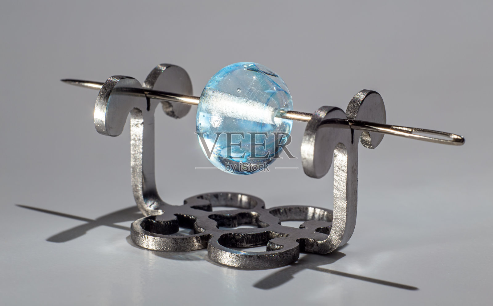 蓝色清澈的玻璃珠上的针照片摄影图片