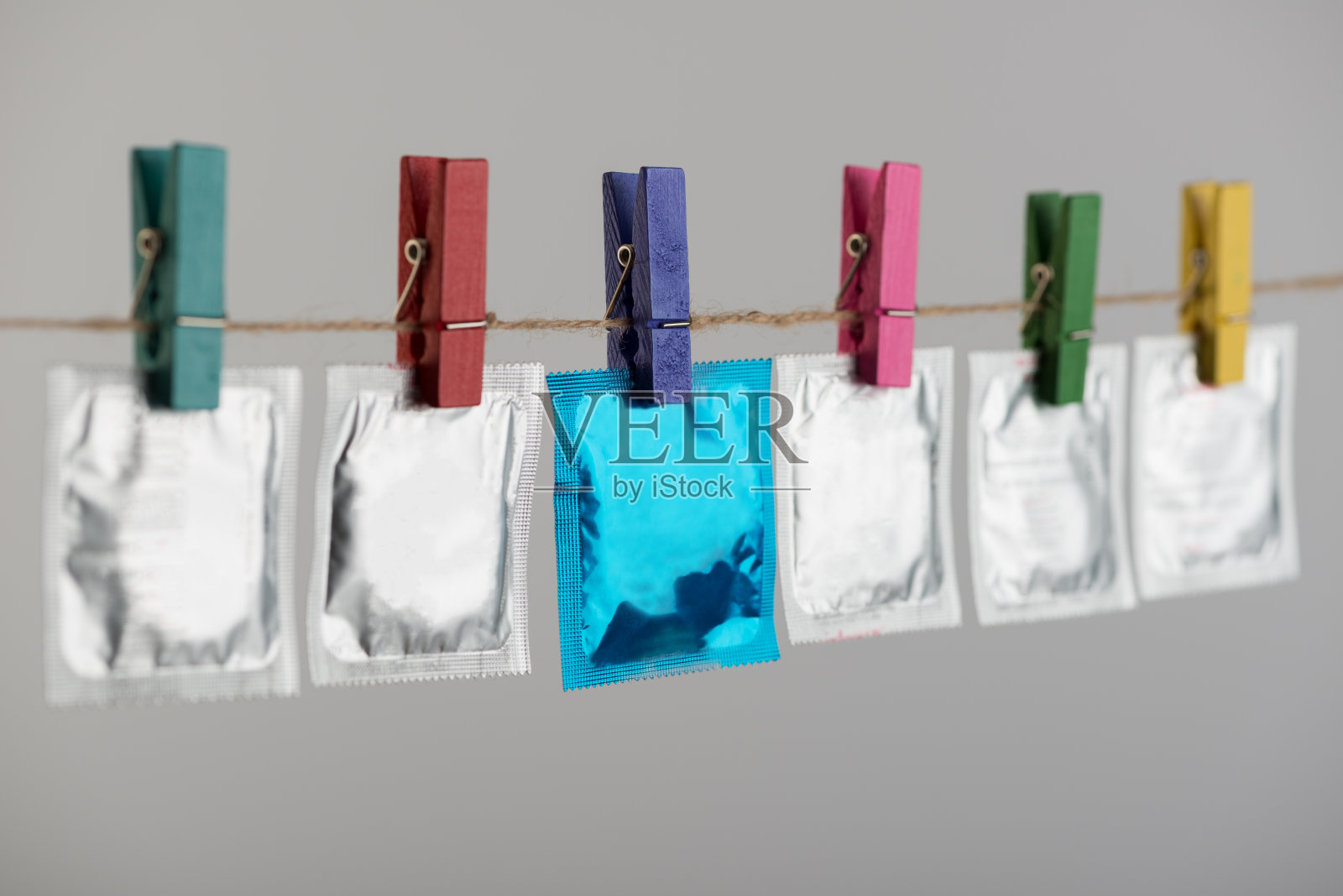 灰色背景下悬挂在绳子上的避孕套照片摄影图片
