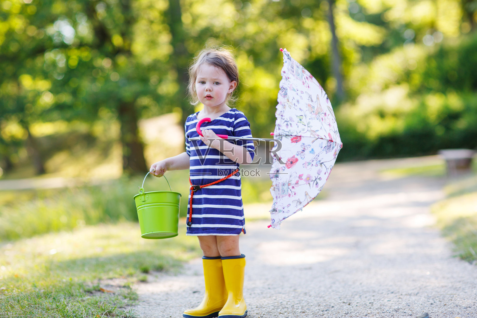 可爱的小孩穿着黄色雨靴和雨伞照片摄影图片