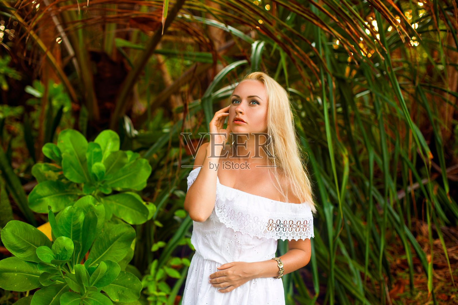 在棕榈阴影下摆姿势的女人照片摄影图片