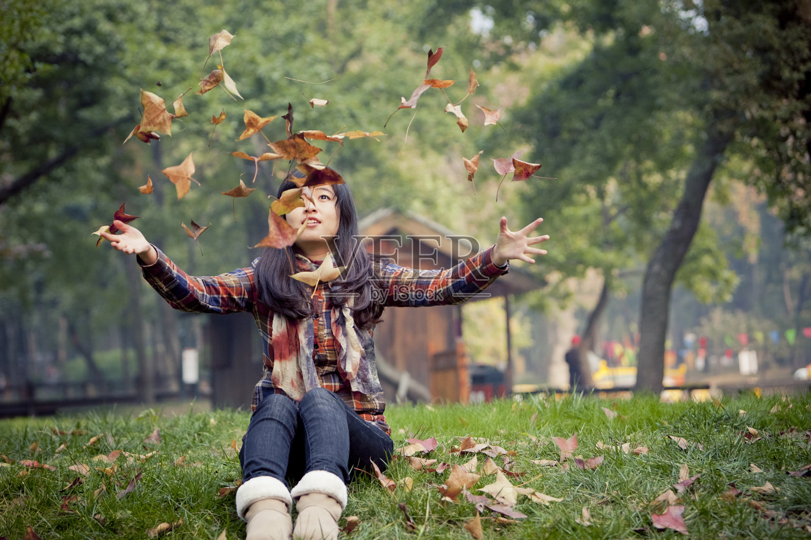 快乐年轻的亚洲女人在户外玩枫叶。照片摄影图片
