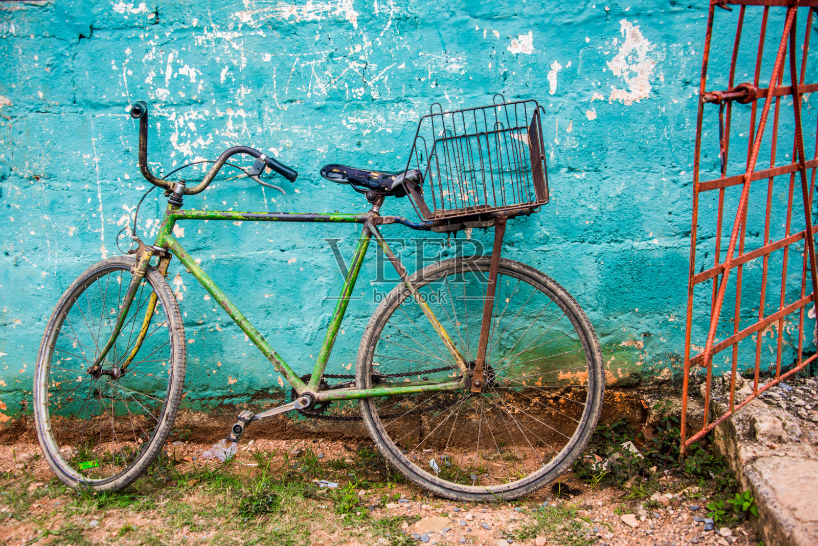 旧的绿色自行车在蓝绿色的墙和红色的门照片摄影图片