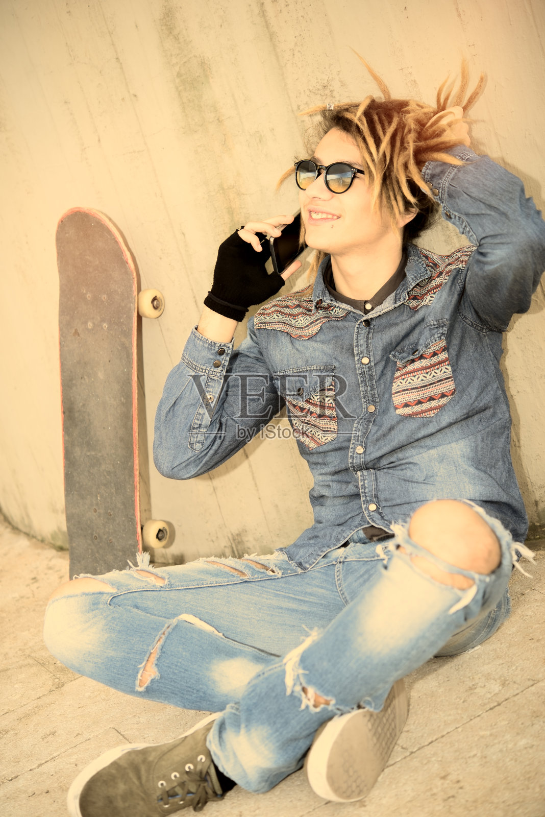 年轻人坐在智能手机的暖色调滤镜上照片摄影图片