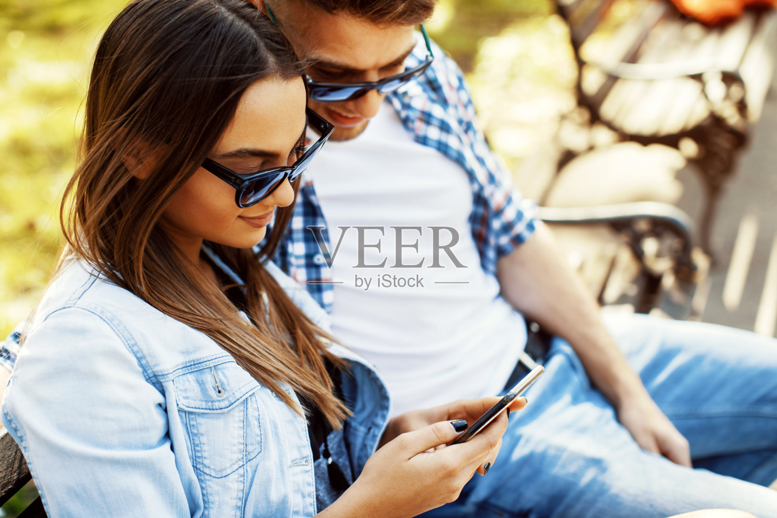 年轻夫妇在公园里玩智能手机照片摄影图片