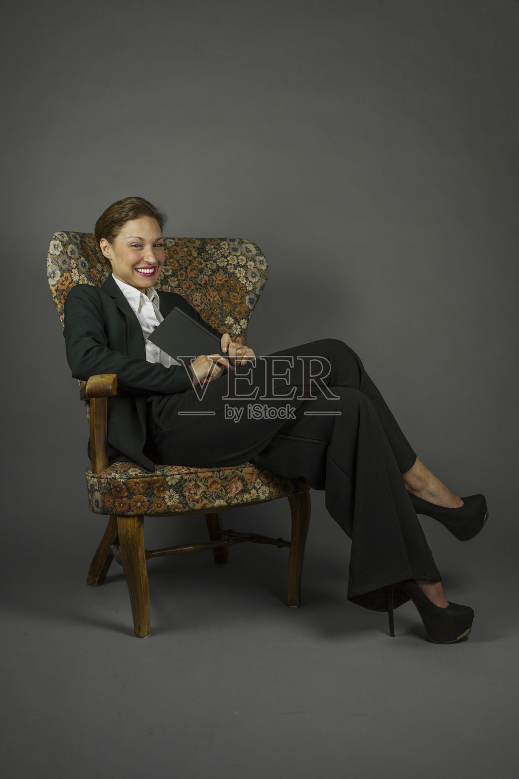 年轻性感的女人在男人的黑色套装坐在阅读照片摄影图片