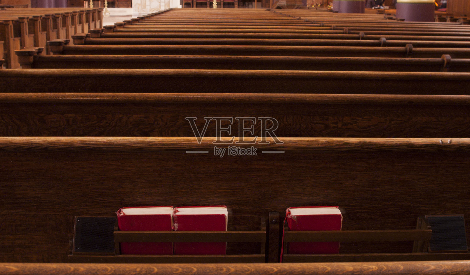天主教堂里一排排的长椅,上面放着三本红色的《圣经》照片摄影图片