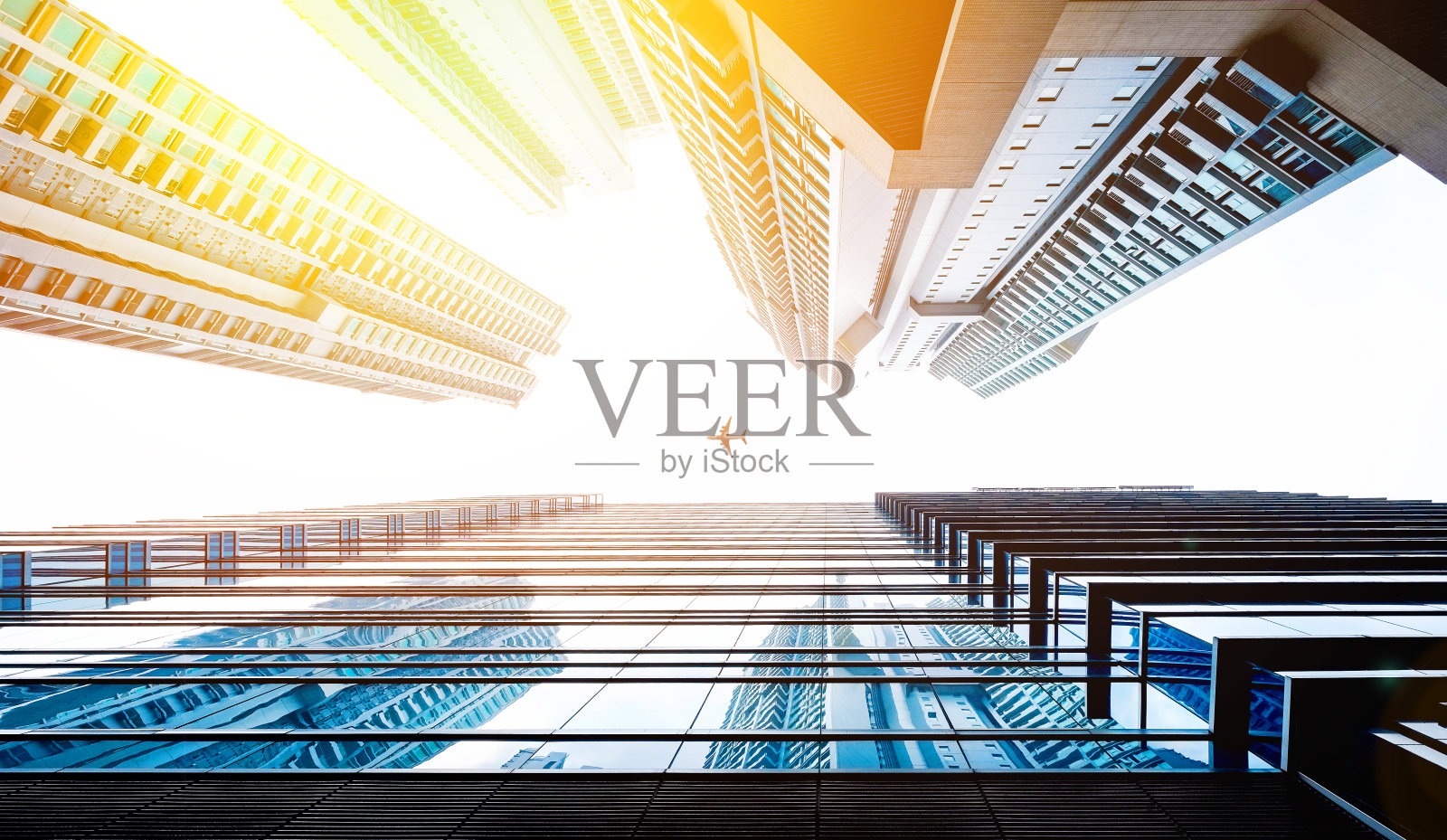 仰望摩天大楼,可以看到天空、阳光和飞机照片摄影图片