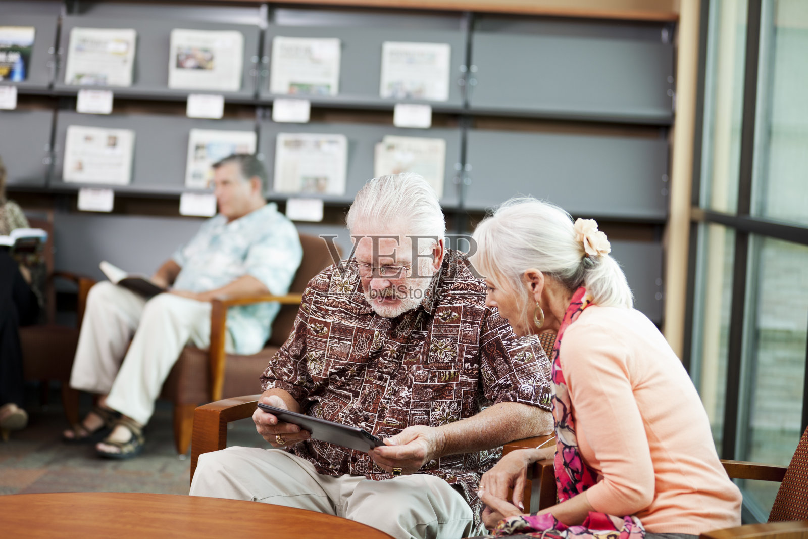 老人和他的妻子在看数字平板电脑上的新闻照片摄影图片