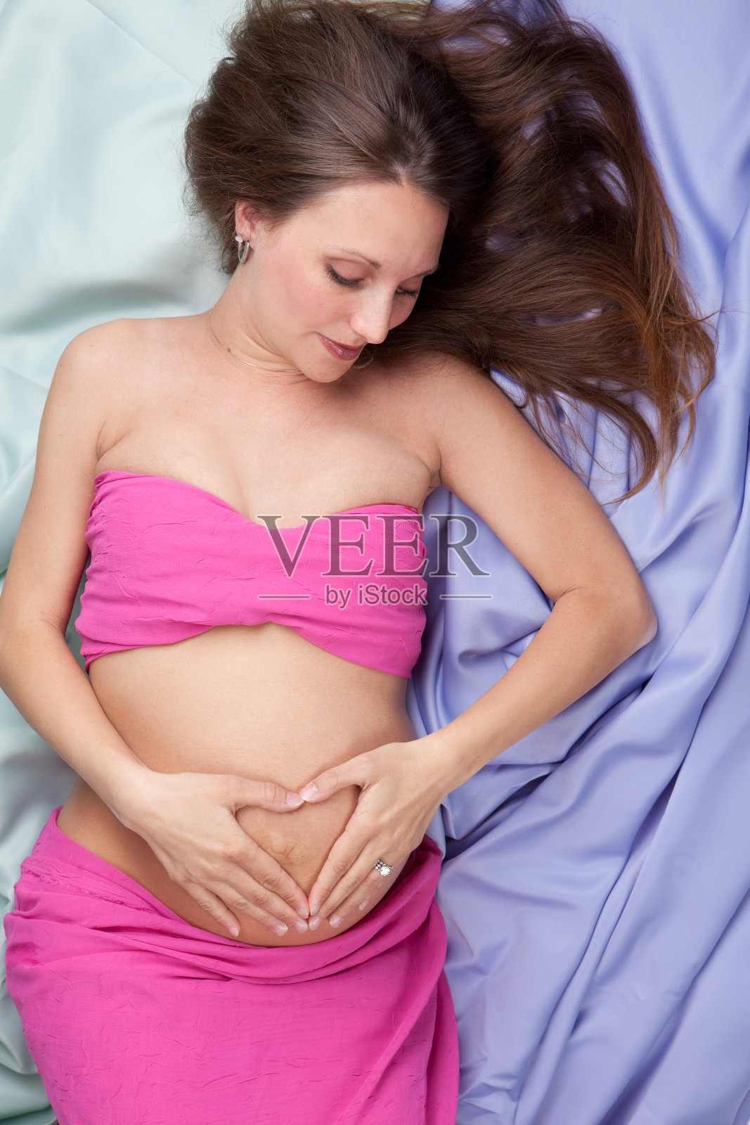 美丽的孕妇做心脏形状照片摄影图片