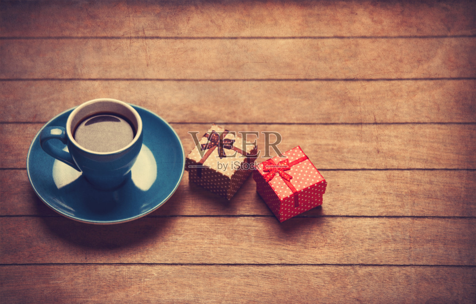 木桌上放着一杯咖啡和礼品盒。照片摄影图片