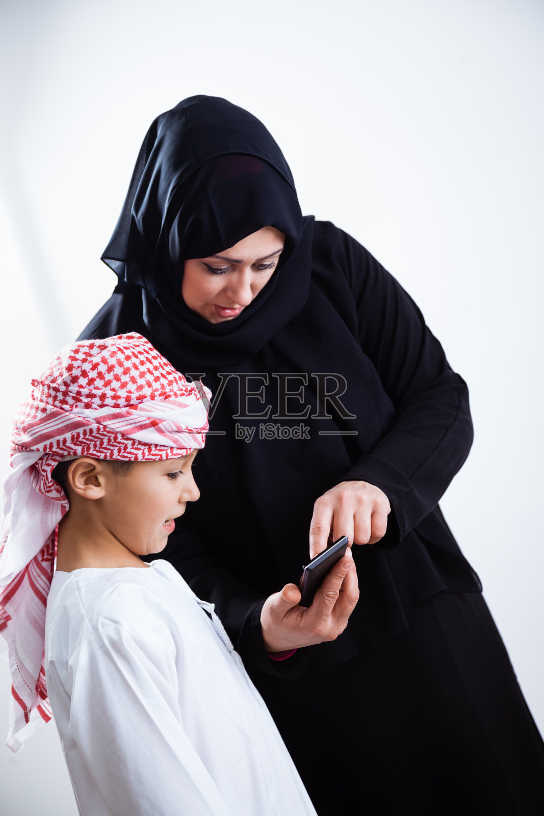 阿拉伯母亲和她的儿子使用智能手机照片摄影图片