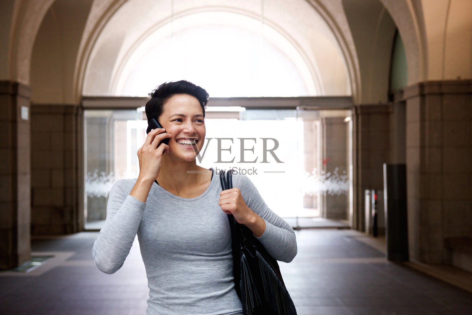 快乐的年轻女子带着手机和包包走着照片摄影图片