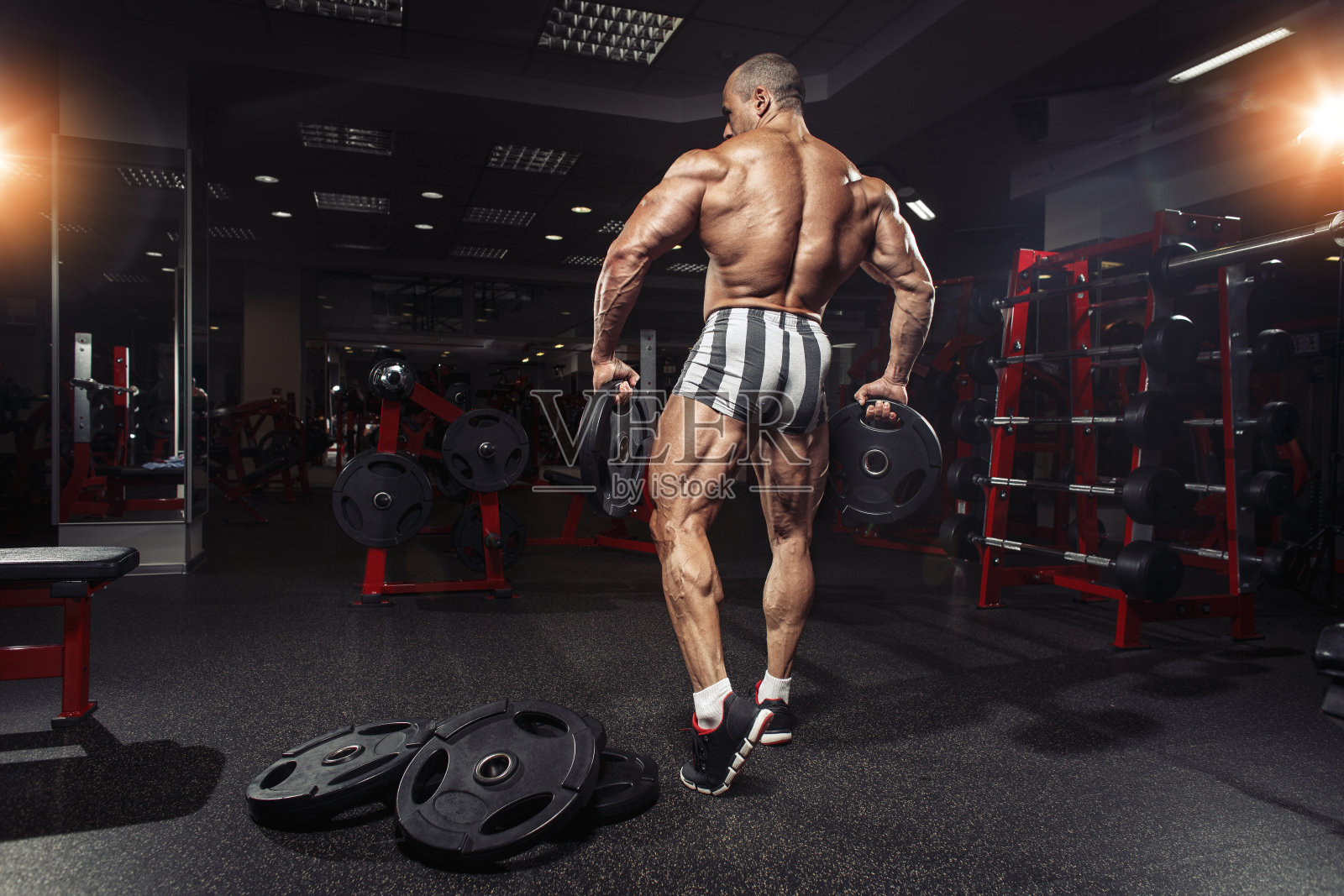 强壮的运动员,手握重物的运动员。后视图。健身房。照片摄影图片