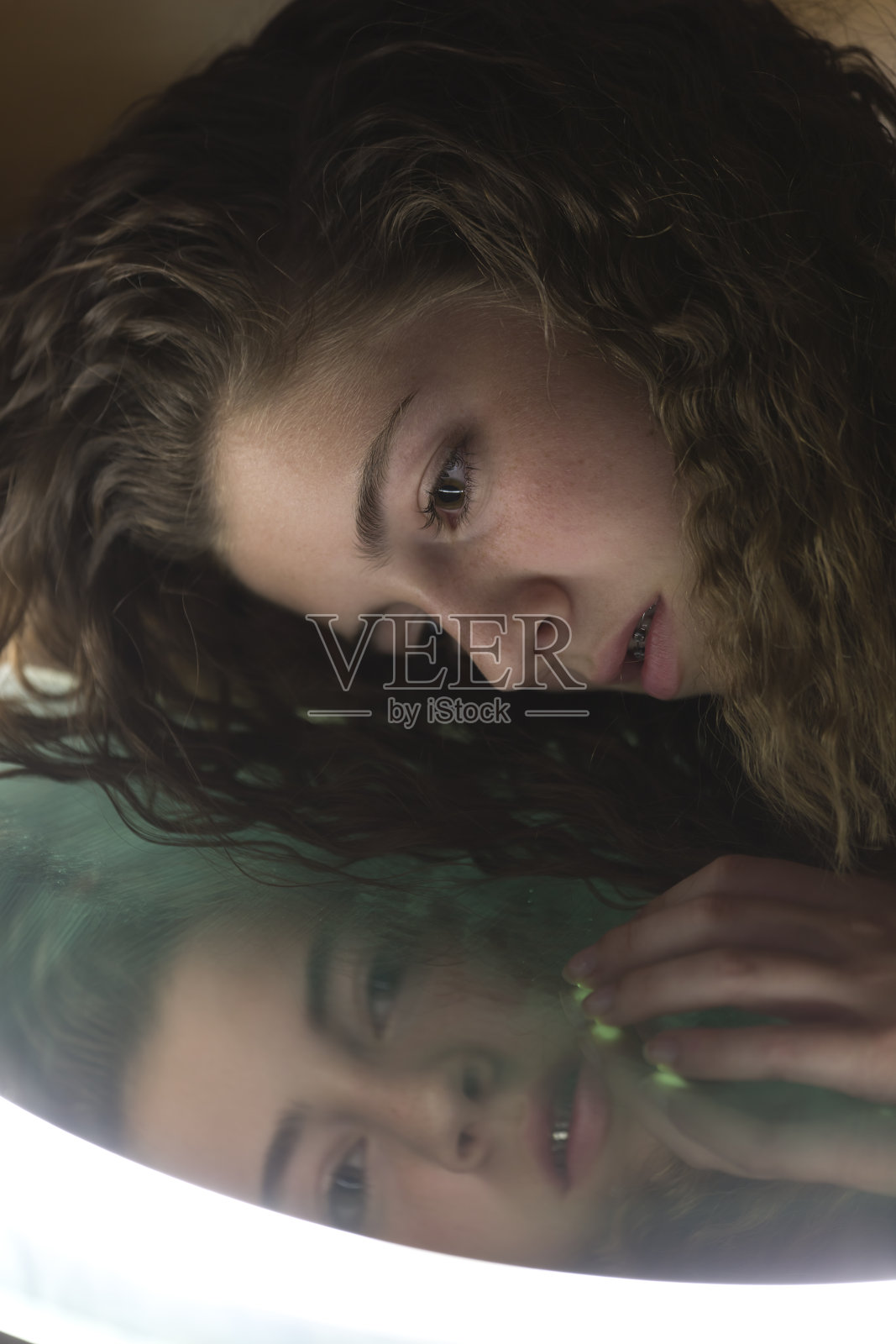 一个对着镜子看自己的少女照片摄影图片