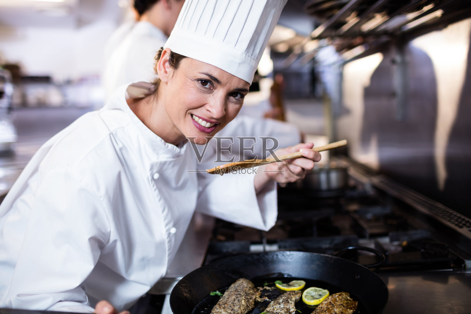 厨师在厨房里闻到炸鱼的味道照片摄影图片