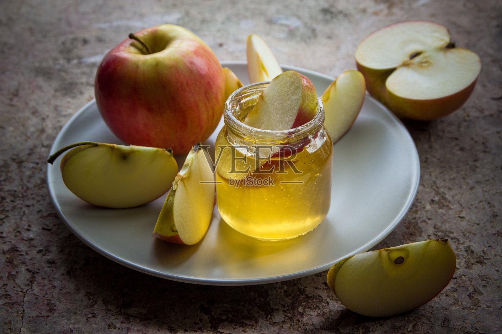 有机蜂蜜在玻璃罐和红苹果在盘子里照片摄影图片