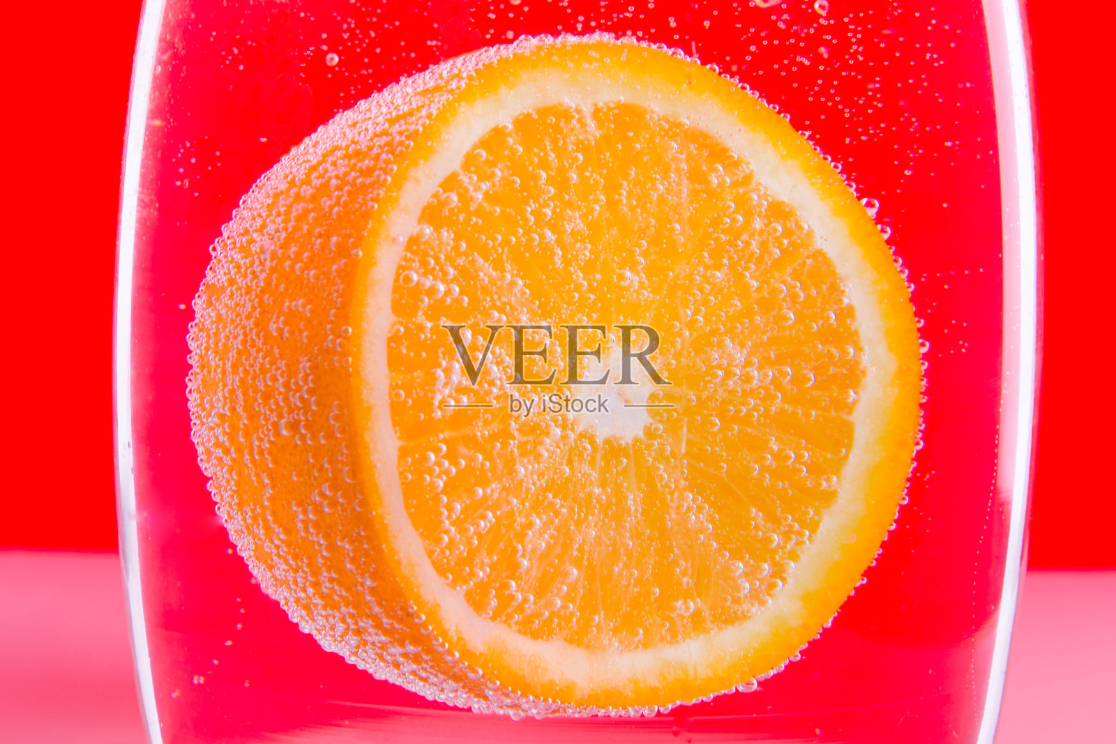 切片橙色的水与气泡在红色的背景照片摄影图片