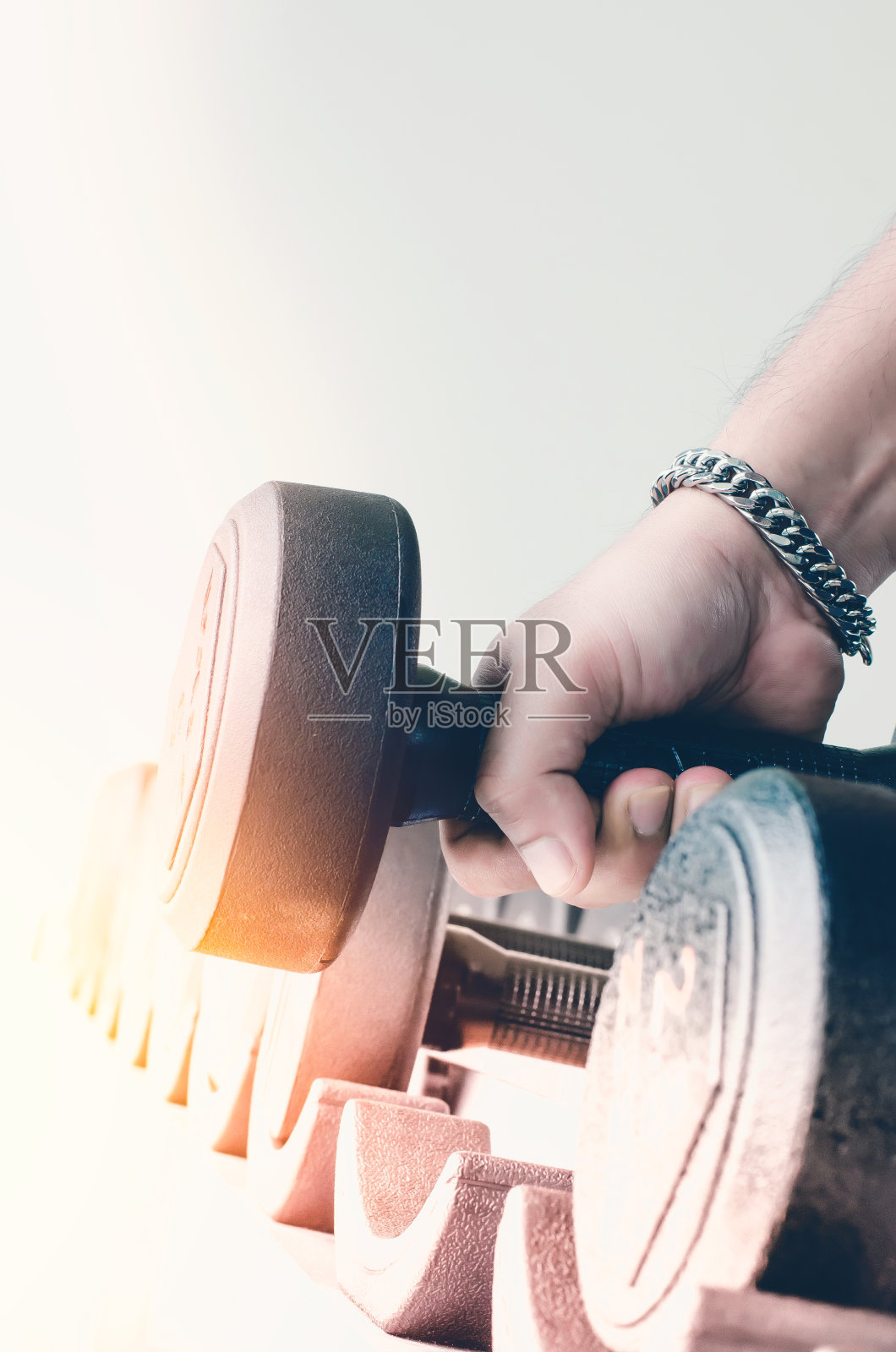 强壮的男人的手拿着一个沉重的哑铃在体育馆照片摄影图片