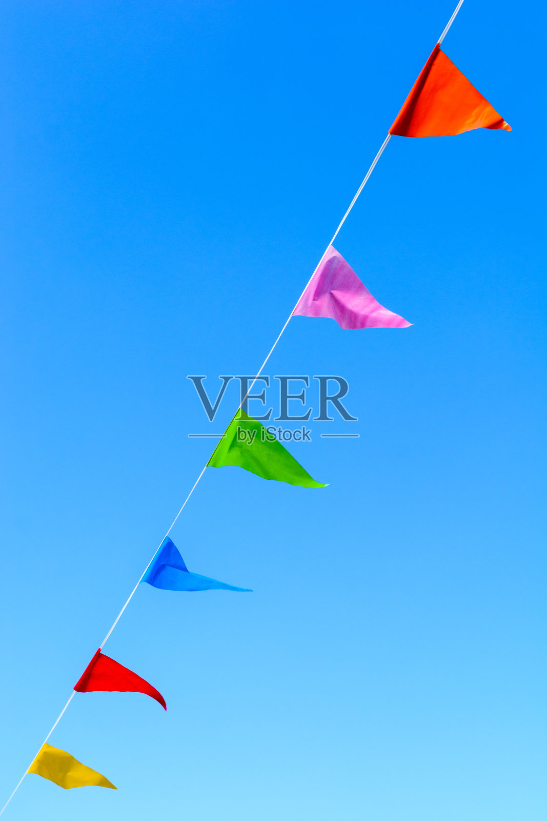 蓝色天空映衬着五彩缤纷的小旗帜。照片摄影图片