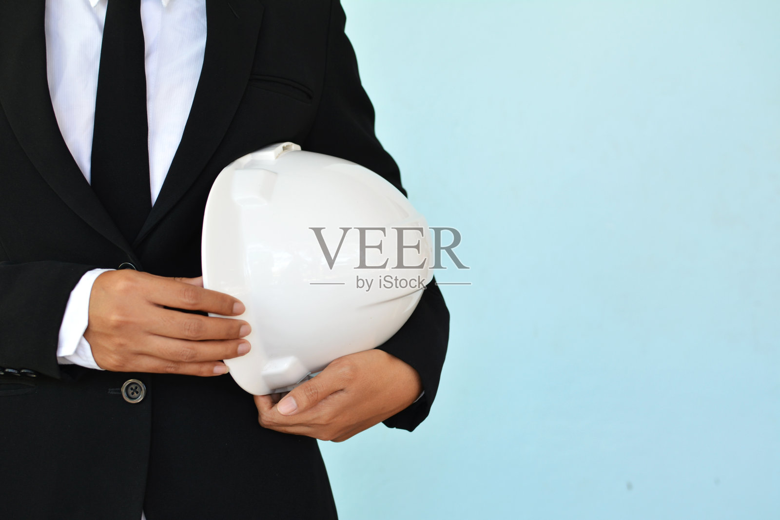 在蓝色背景上拿着帽子的工程师的肖像照片摄影图片