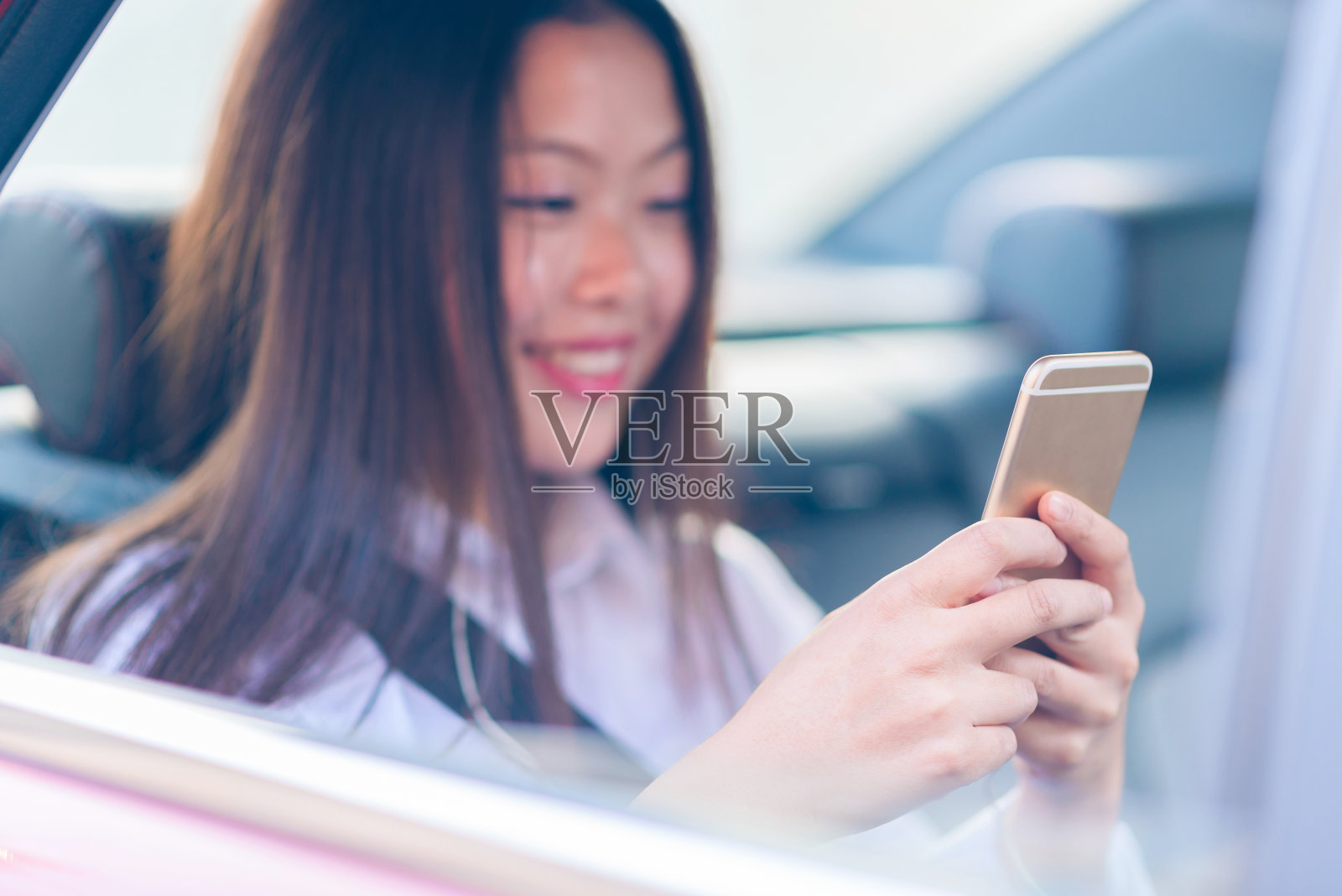 中国年轻女子在车里使用智能手机。照片摄影图片