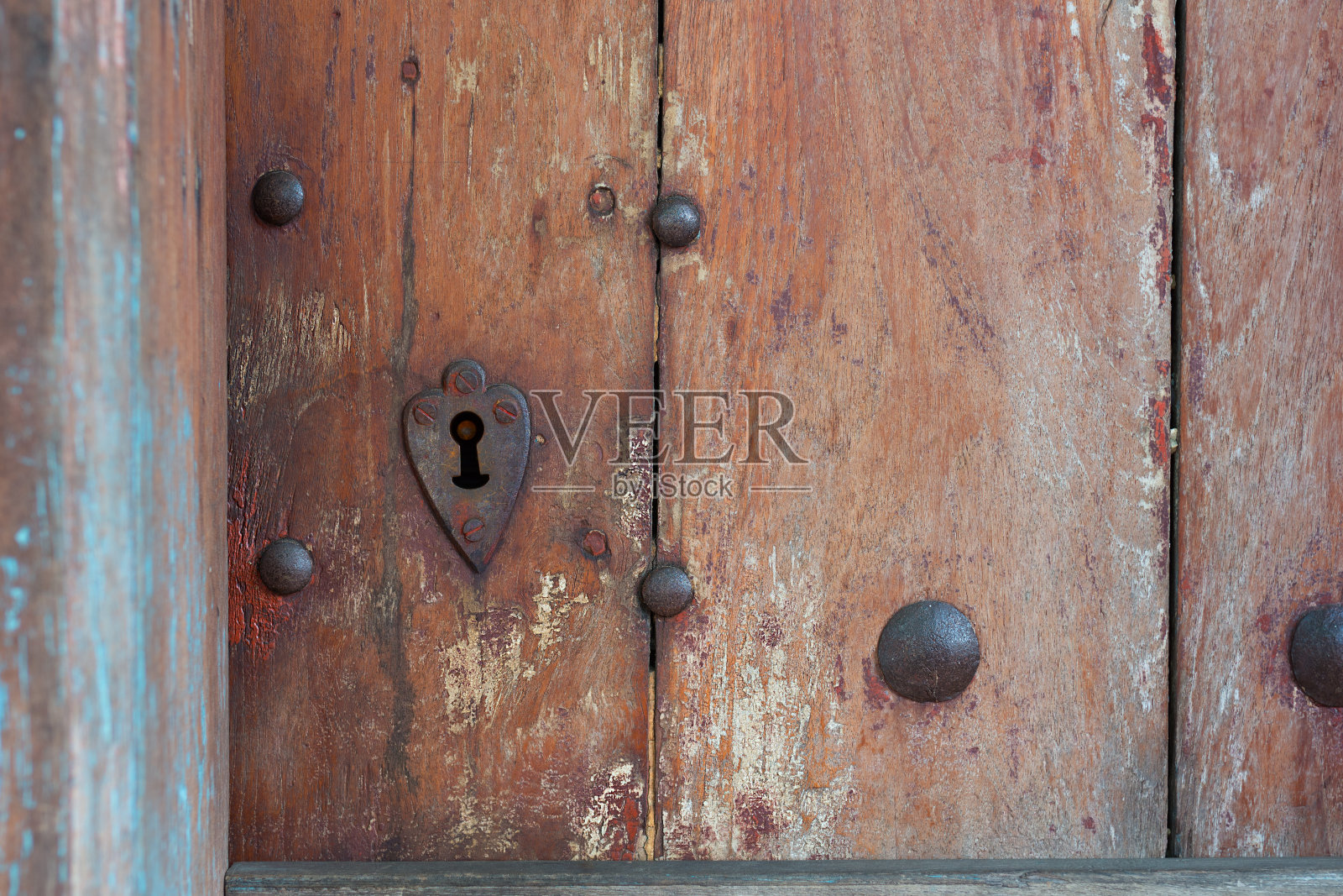 心形锁孔环绕在旧木门上。照片摄影图片