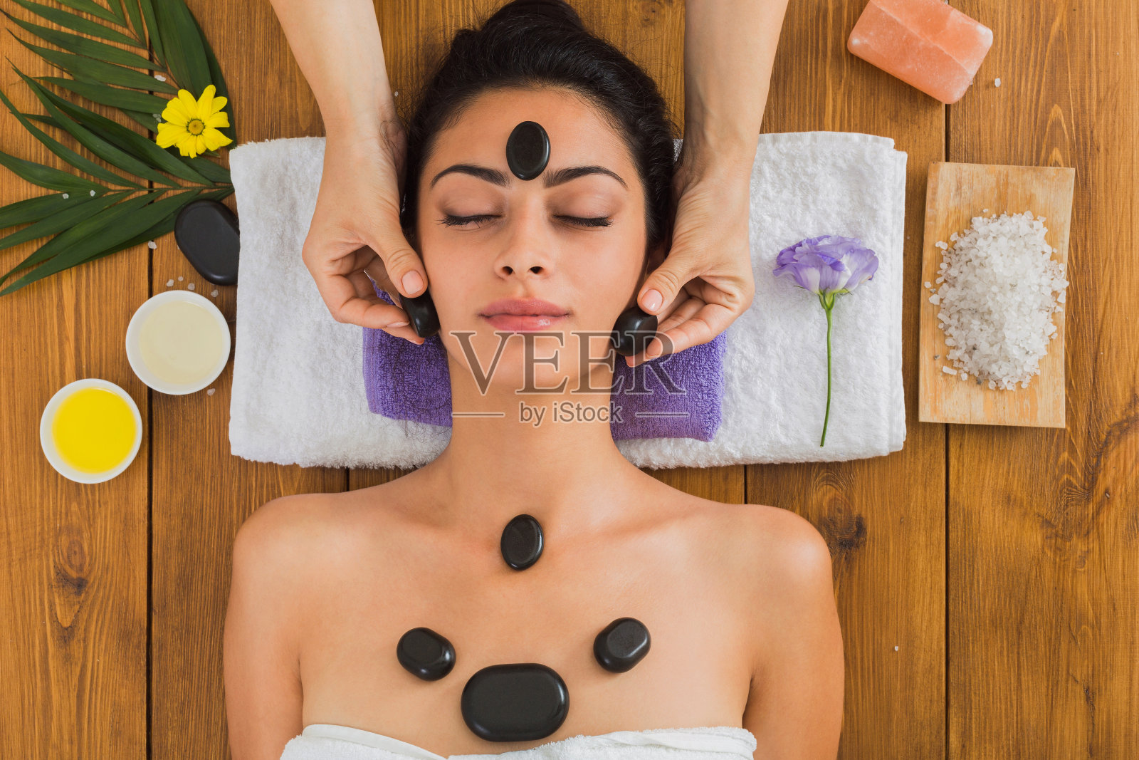 美容师在健康中心为女性制作石头按摩spa照片摄影图片