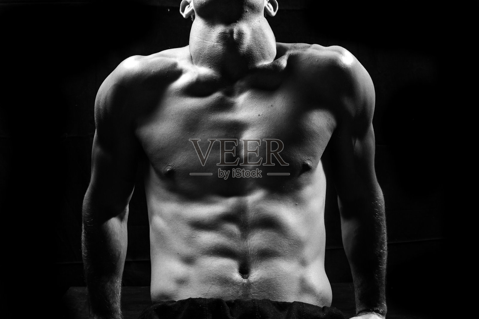 男性健身模型显示肌肉在工作室与黑色背景照片摄影图片