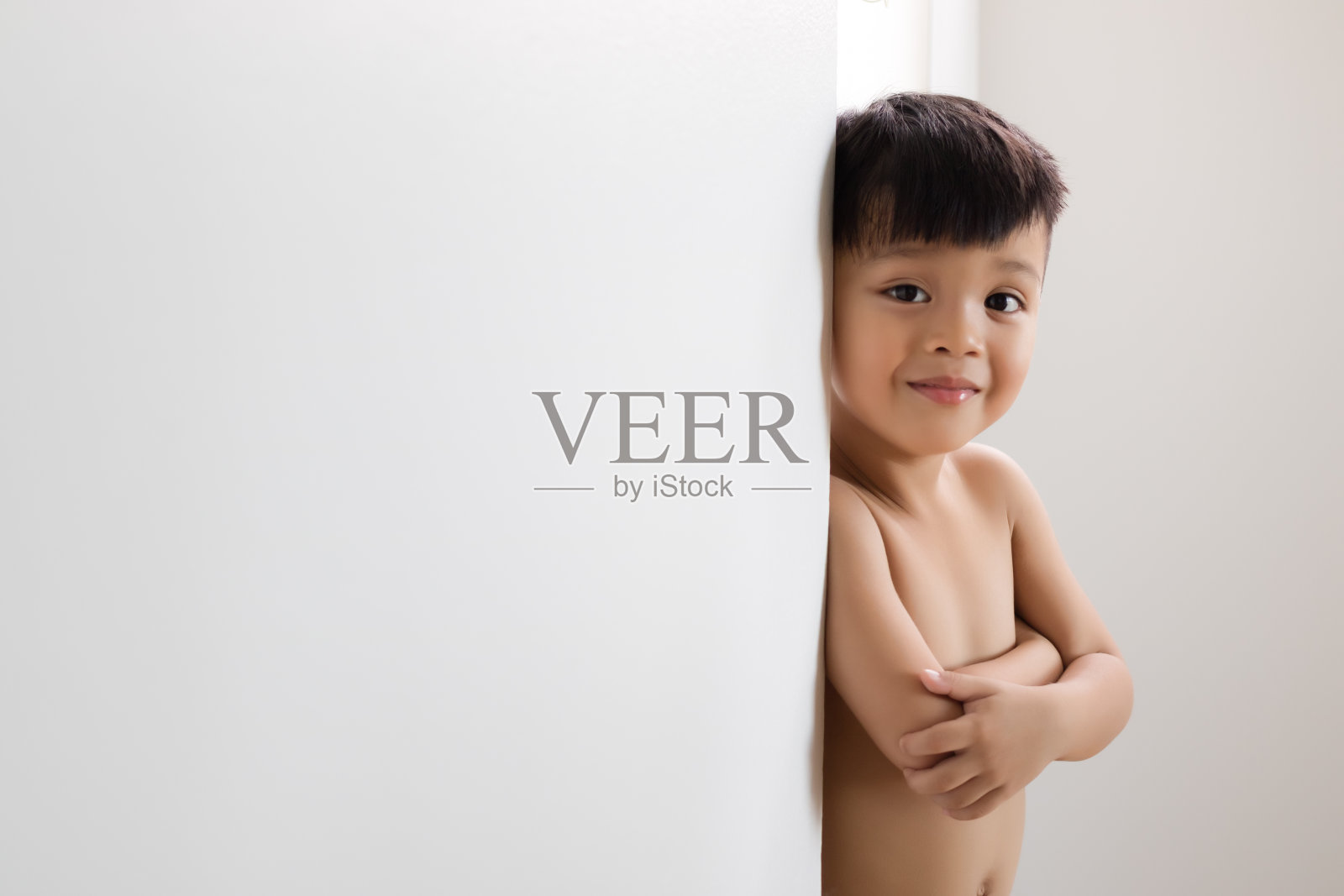 可爱的亚洲男孩在白墙上。照片摄影图片