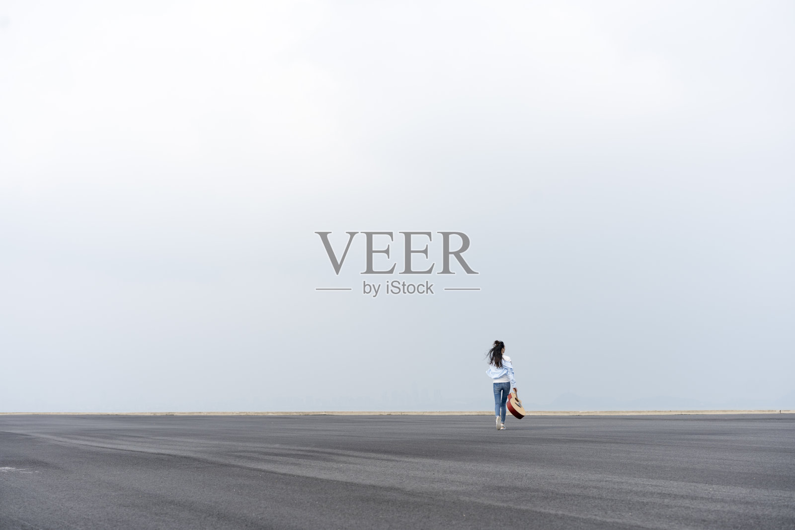 年轻风格的女人拿着吉他在天空中行走照片摄影图片