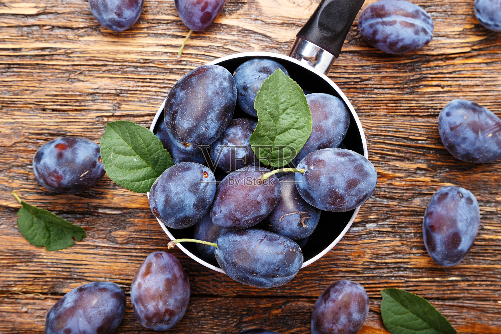 棕色木桌上放着成熟的李子,照片摄影图片