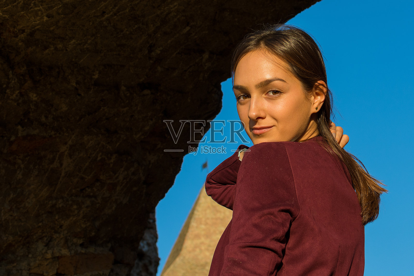 日落时分,一个美丽的女孩在一座中世纪城堡前摆姿势照片摄影图片