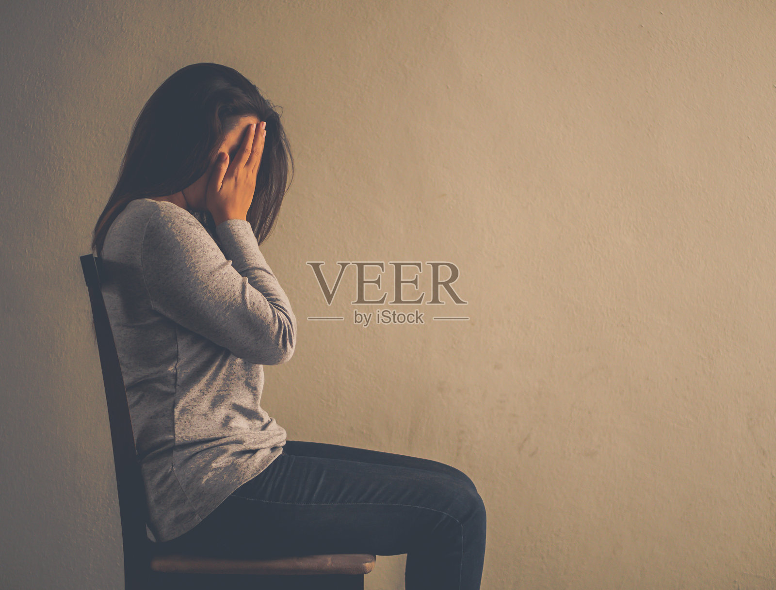 情绪低落的女人在黑暗的房间里坐在椅子上,孤独、悲伤、情感概念照片摄影图片