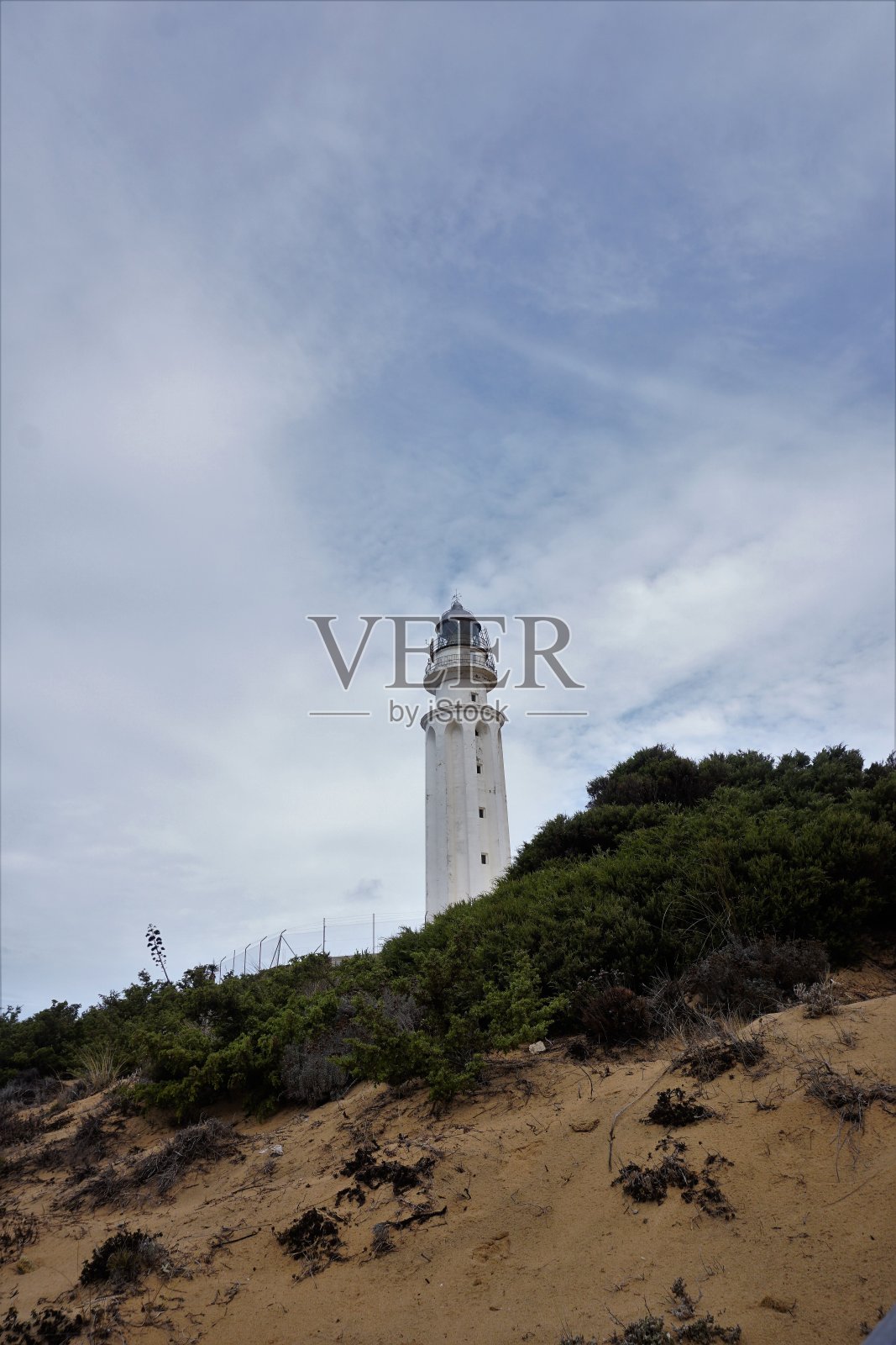 海滩上的灯塔,有灌木丛和云彩照片摄影图片