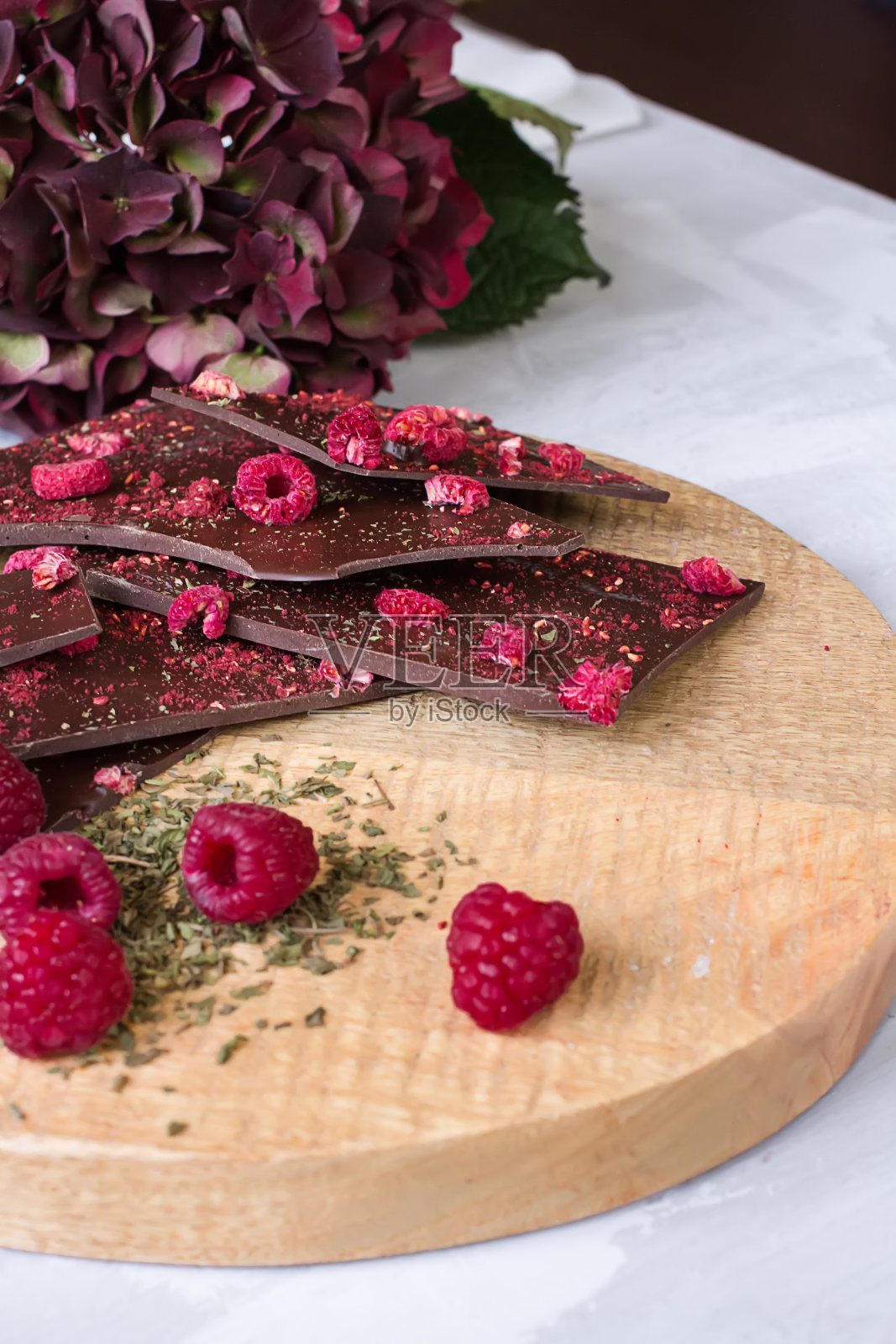 黑巧克力,覆盆子和面包屑放在木板上。光背景。照片摄影图片