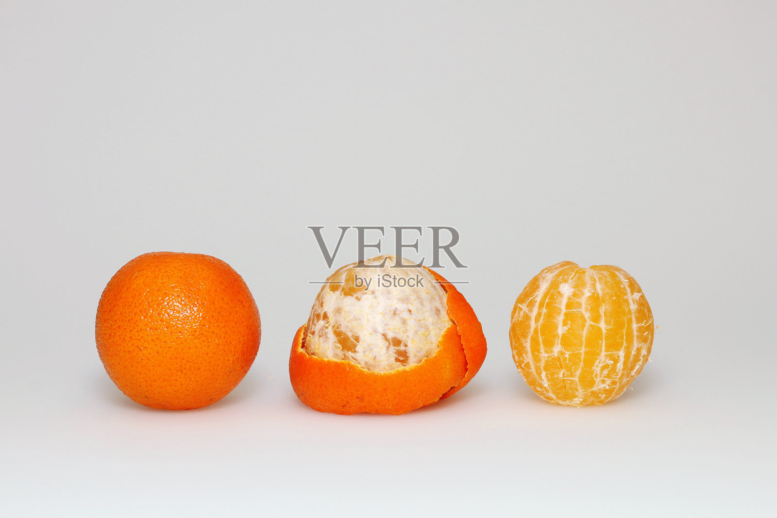 白底上的三个橘子:未清洗、去皮、中间去皮照片摄影图片
