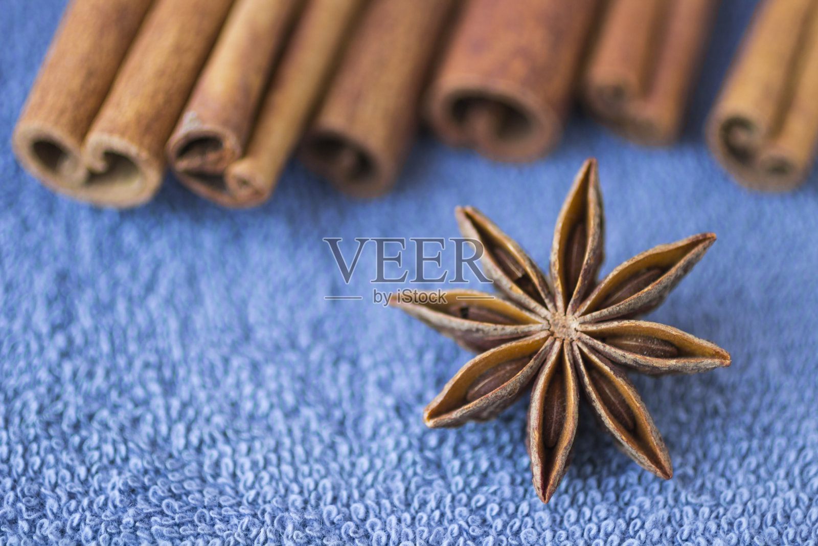 香料:蓝色背景上的八角和肉桂棒。特写镜头。模糊照片摄影图片
