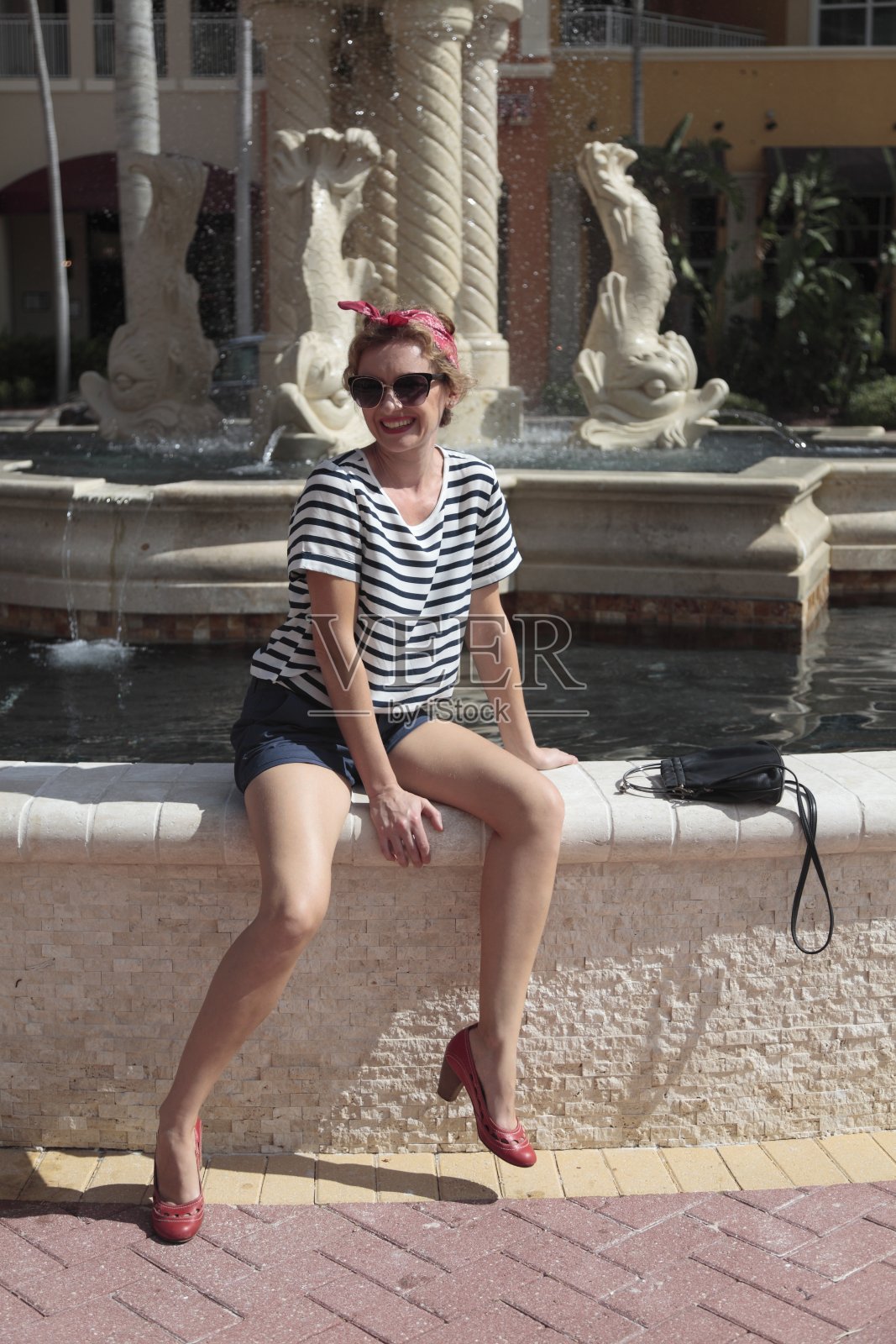 海报女郎坐在喷泉前。照片摄影图片