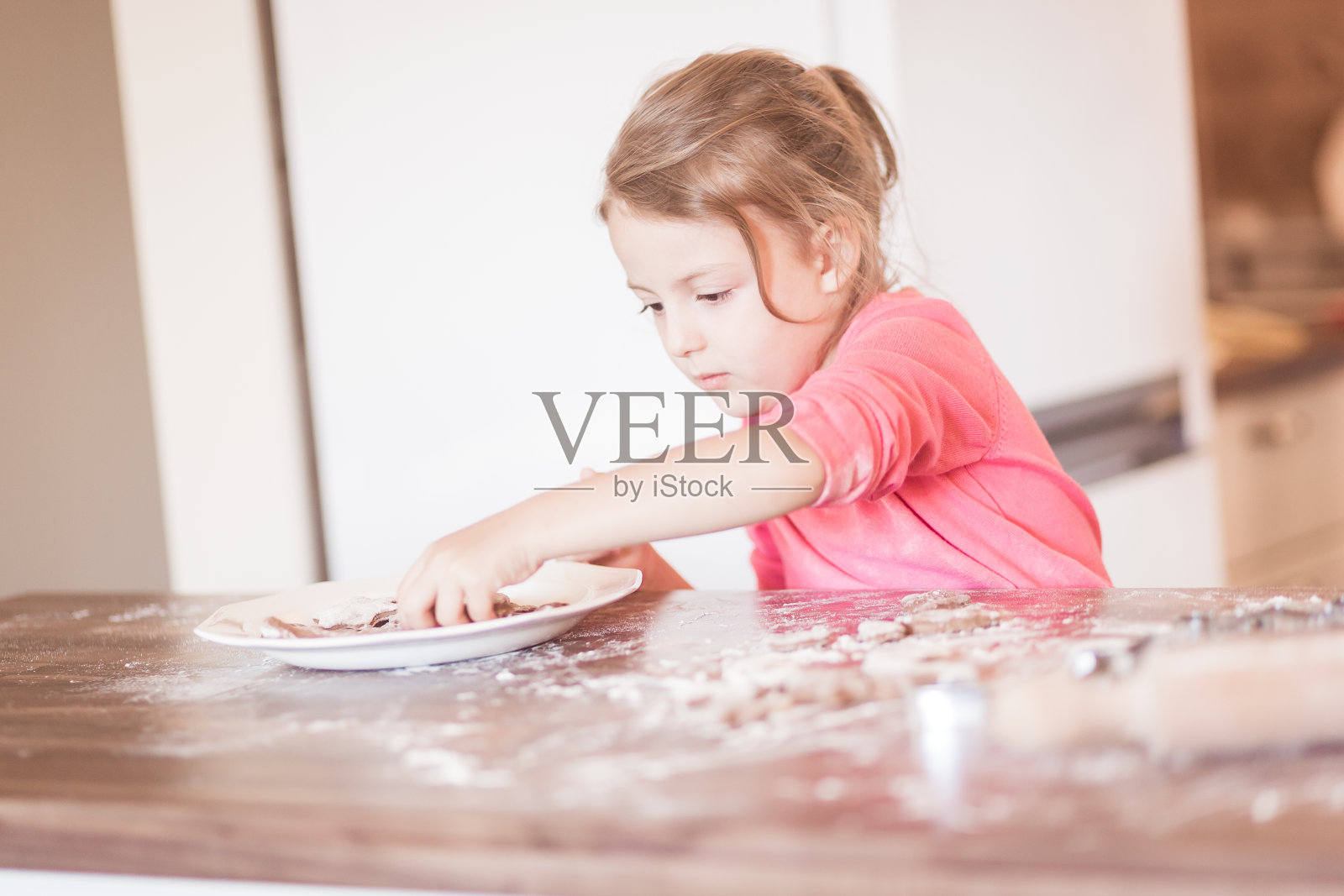 家庭的时刻。家庭的时刻。快乐的小女孩在厨房里做面团照片摄影图片