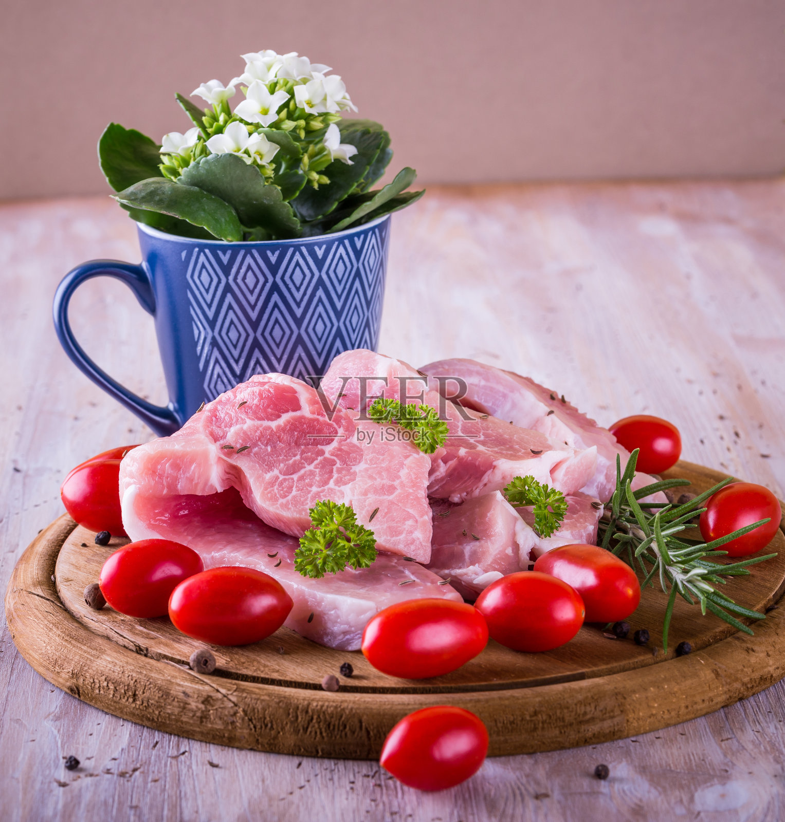方形照片与几长片猪肉与肥肉在边缘。绿色的欧芹枝,单迷迭香和西红柿旁边的肉和花在杯子里。生的食物放在木砧板上。照片摄影图片