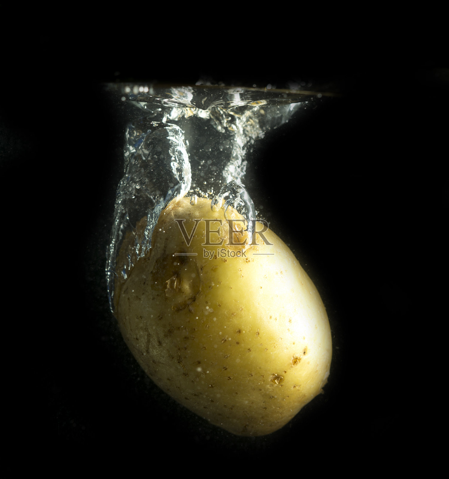 土豆在水和溅在黑色的背景照片摄影图片