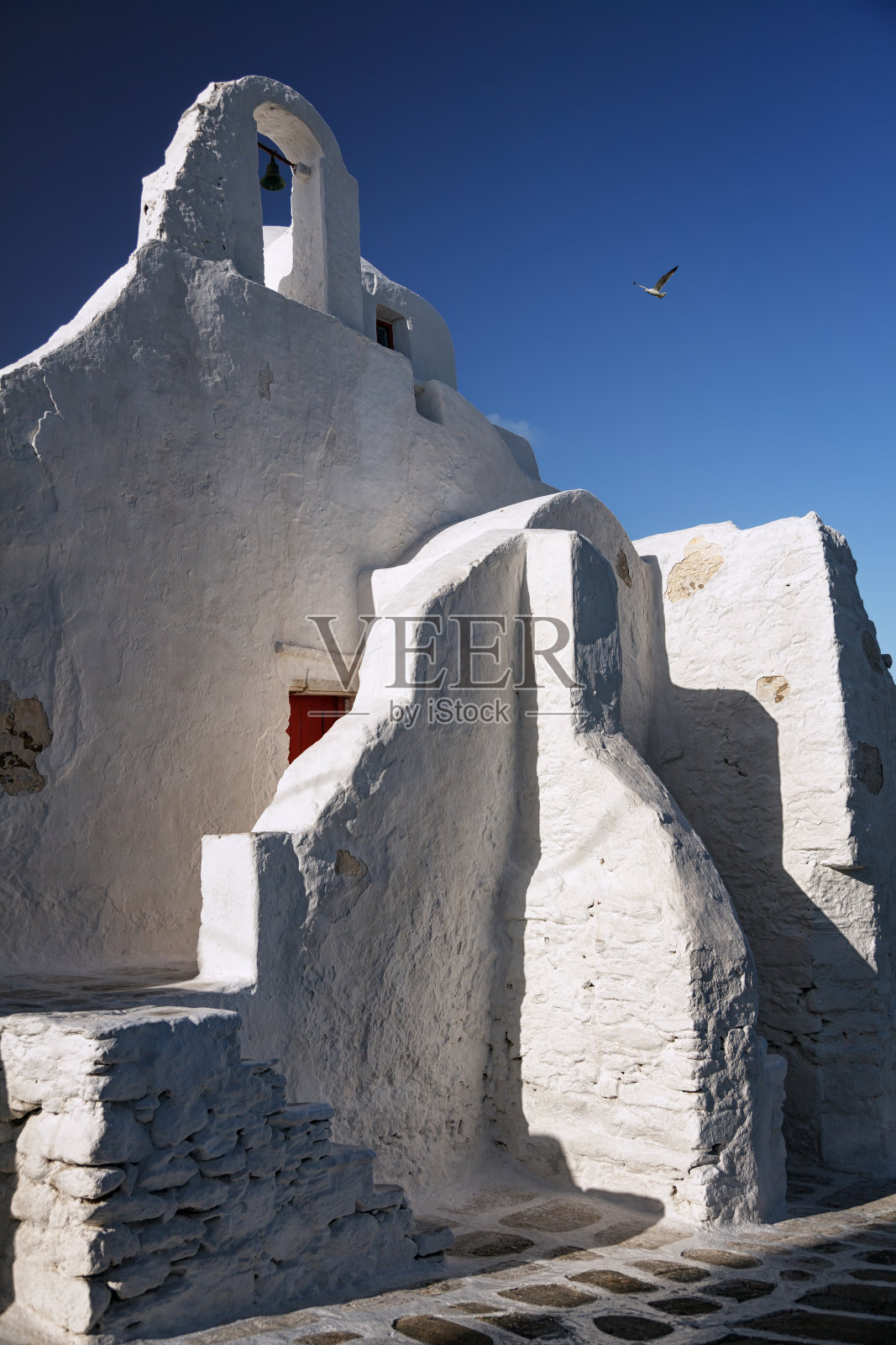 希腊基克拉迪斯米科诺斯岛的帕拉波提亚尼教堂,一只海鸥在飞翔照片摄影图片