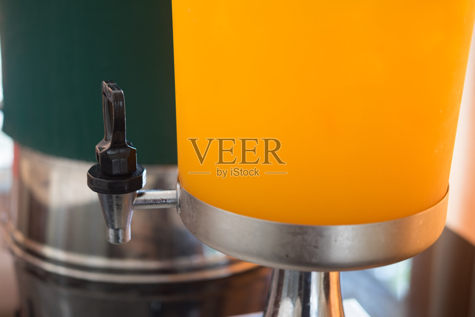 来自热带水果的橙汁在不锈钢的容器里,在早餐吧上提供自助服务照片摄影图片