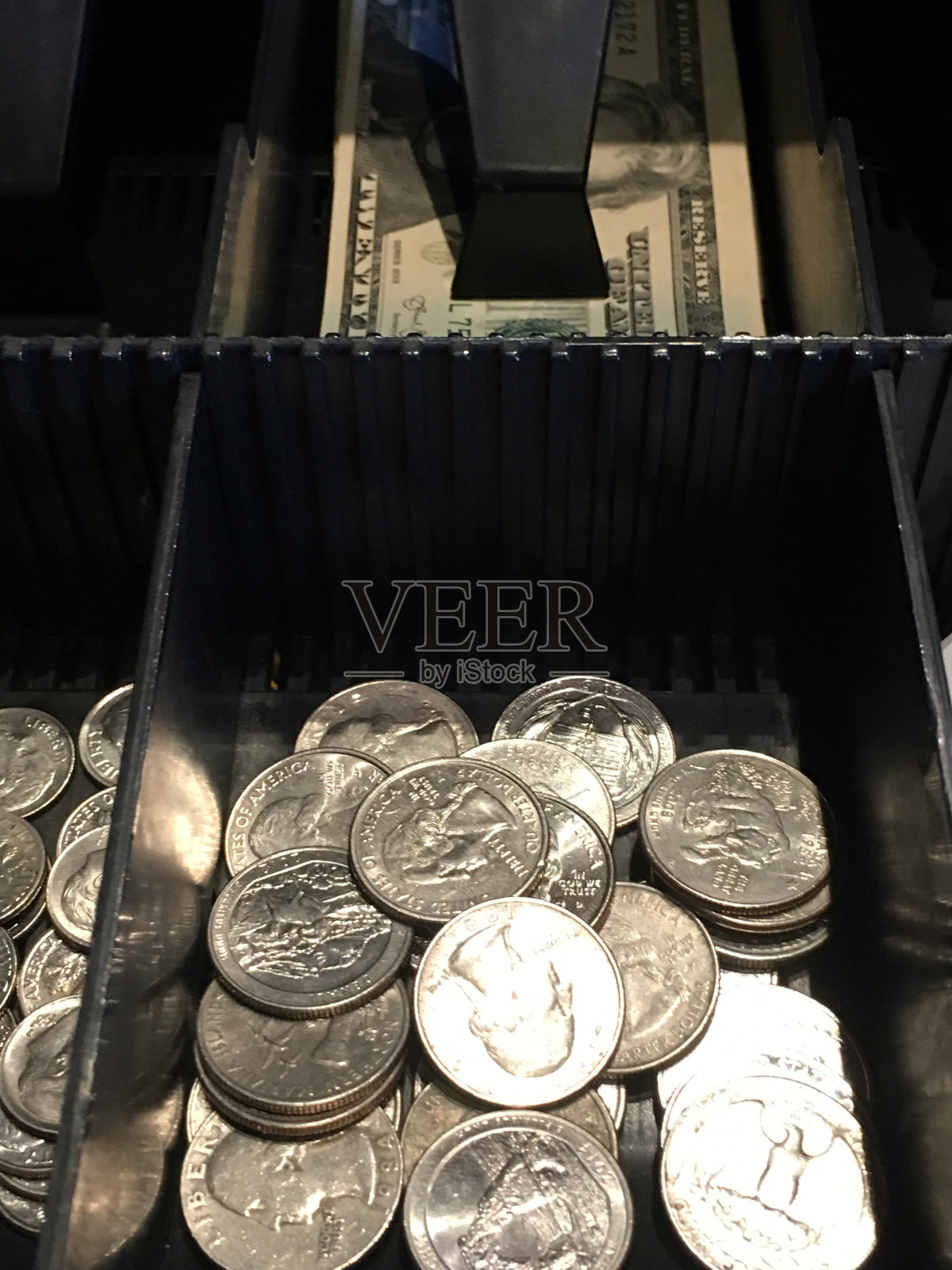 现金抽屉里装满了钱,里面有25美分和20美分的硬币照片摄影图片