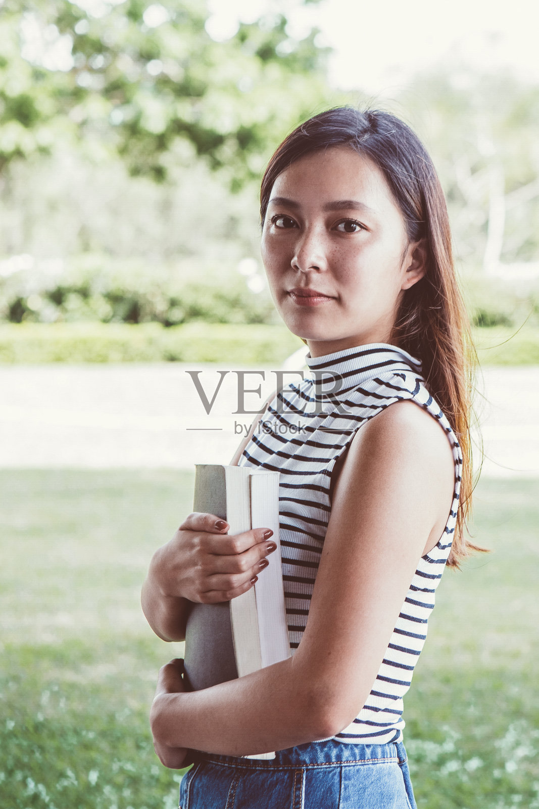 严肃的女学生的肖像与教科书照片摄影图片