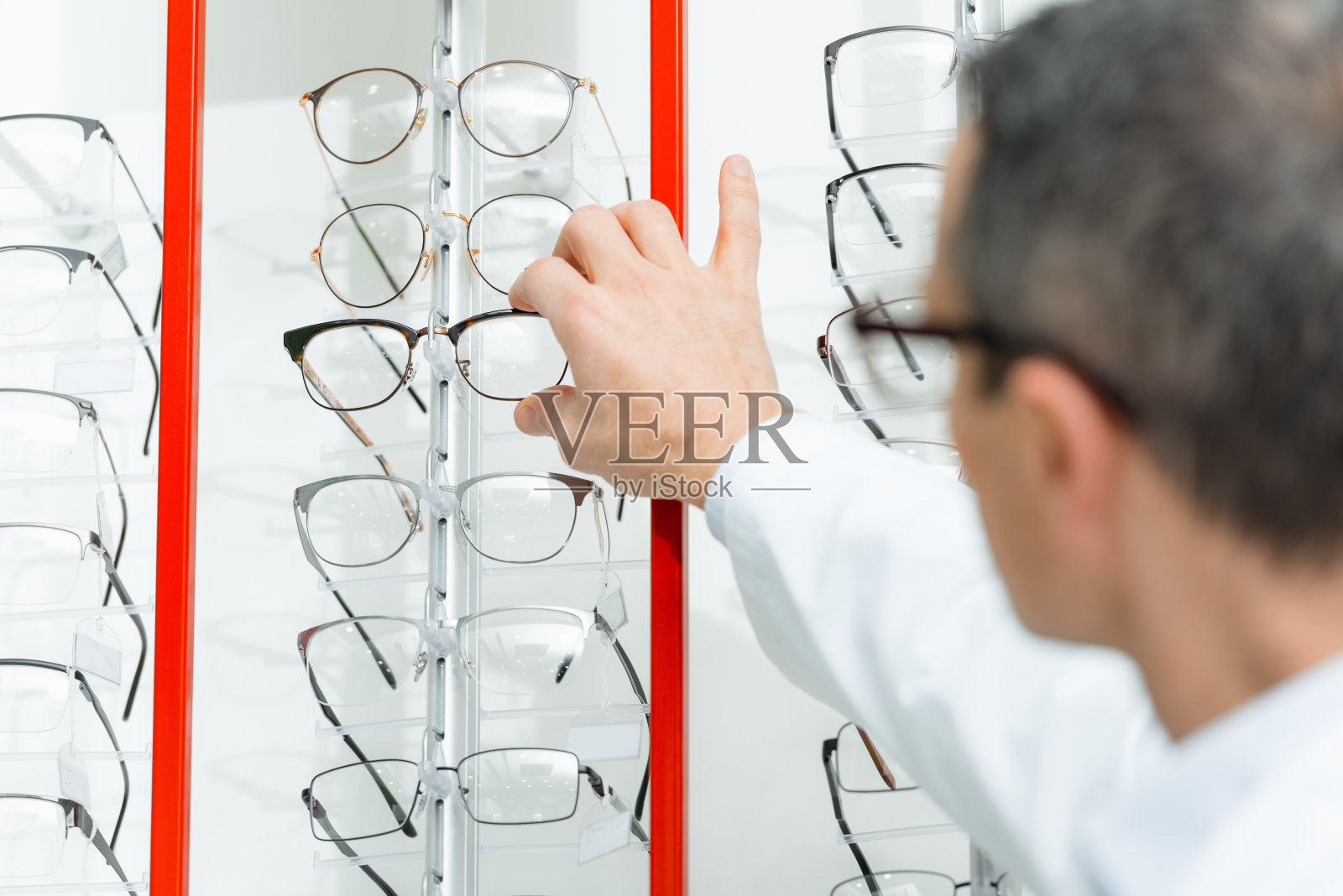 验光师从光学架子上取眼镜时的选择性聚焦照片摄影图片