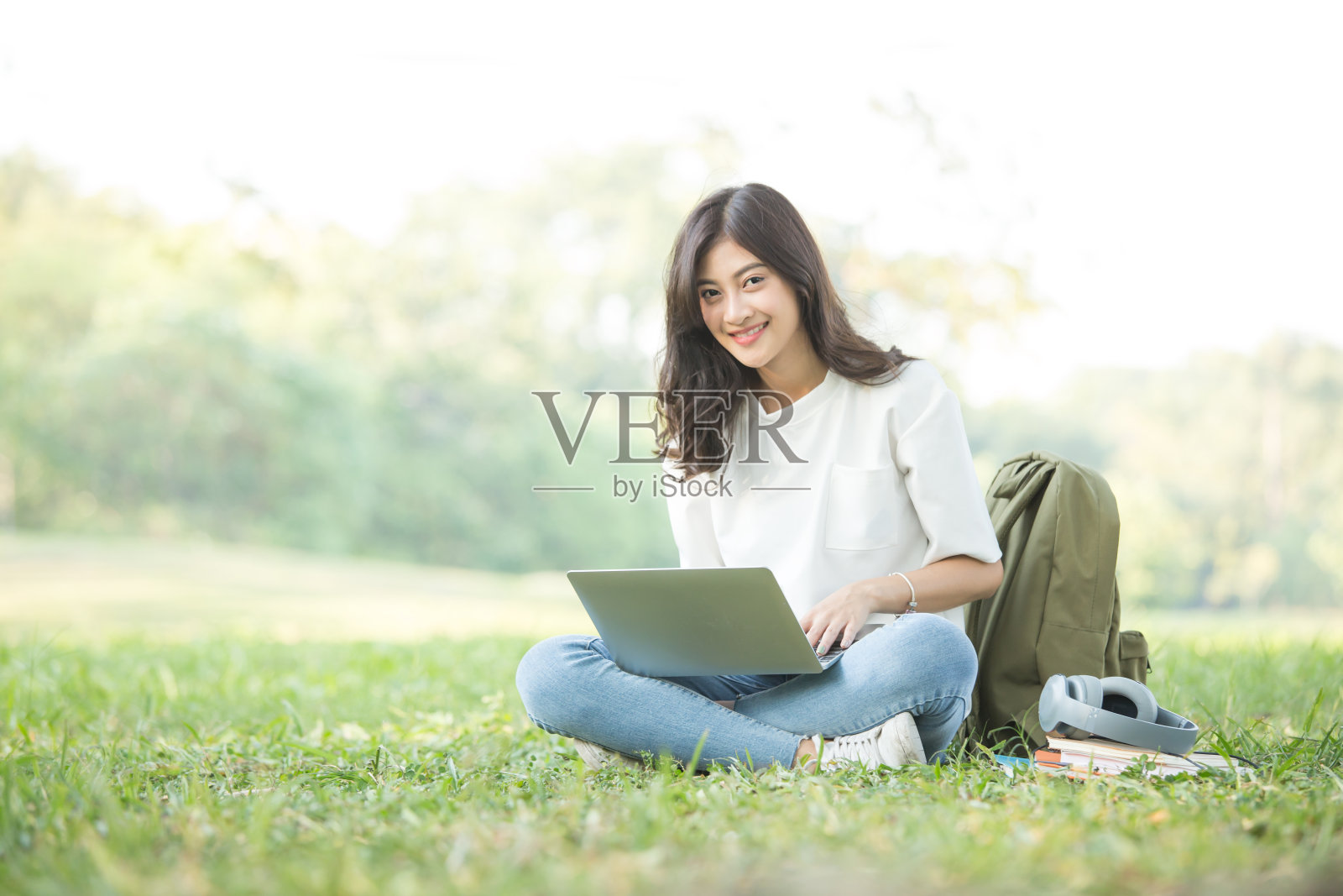 亚洲女人阅读与迷人的微笑在花园。人们生活方式的概念。照片摄影图片